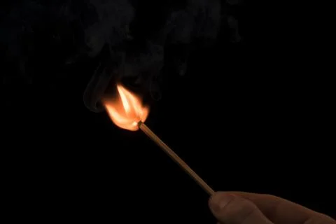 A lighted match on a black background. Hold a lighted match. The fire from th 库存照片
