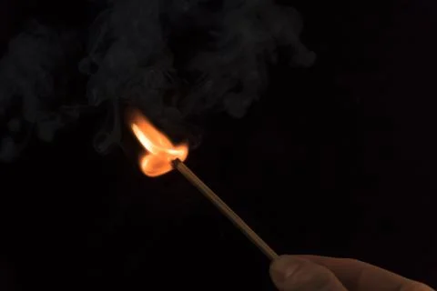 A lighted match on a black background. Hold a lighted match. The fire from th Stock Photos