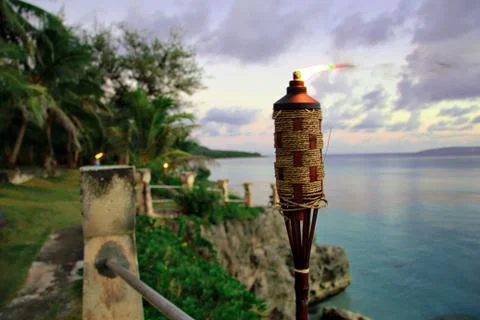 Lighted tiki torch on the a cliffside by the beach Stock Photos