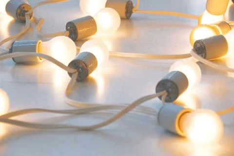 Lighted white bulbs joined by a continuous cable Stock Photos