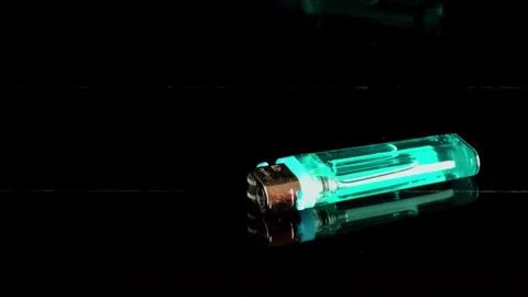 Lighter placed on a black surface with green color highlight at night Video stock 340461882