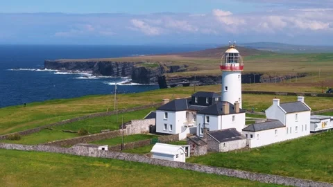 Lighthouse and Adjacent Buildings Amidst Rolling Fields at Loop Head Stock Footage 336028281