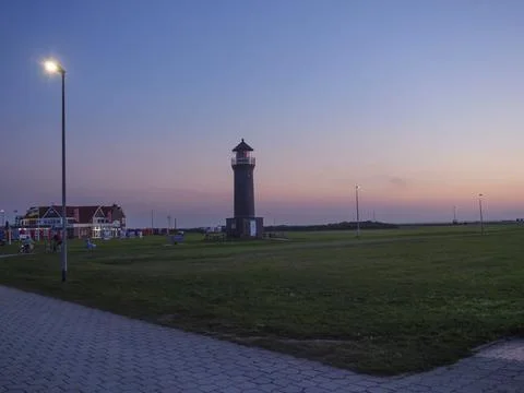 Lighthouse and building at dusk, with soft light over the horizon and a green Fotos de archivo