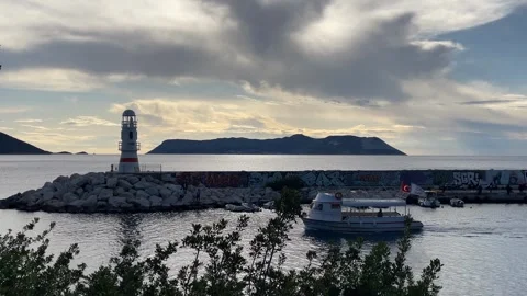 Lighthouse and graffiti-covered wall by calm sea at sunset with distant isl.. Stock Footage 329621647