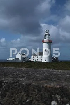 Lighthouse and sky on the irish coast. Stock Photos