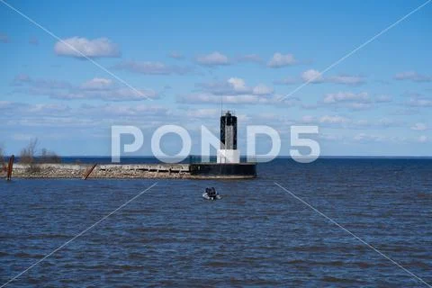 Lighthouse on the bay fishermen in a boat Stock Photos