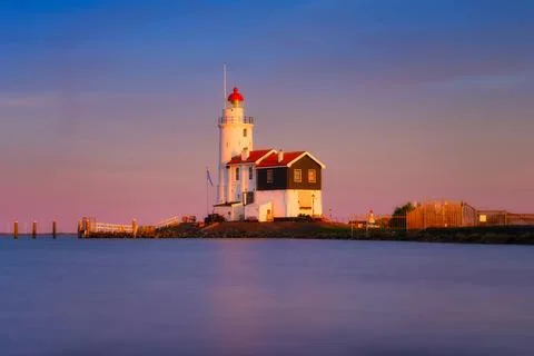 A lighthouse on the beach during sunset. A landmark in maritime navigation. L Stock Photos