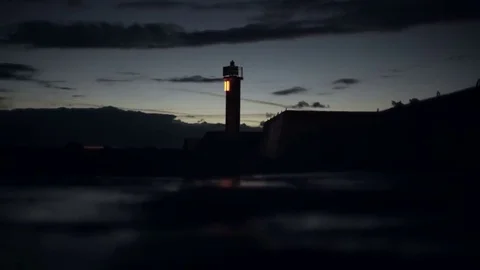Lighthouse bokeh light flashes on the pier reflection in the late evening Stock Footage 69205340