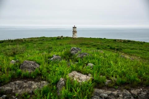 Lighthouse centered on the background of the sea in cloudy weather Stock Photos