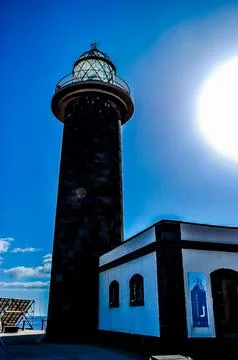 A lighthouse is on a cliff overlooking the ocean Stock Photos