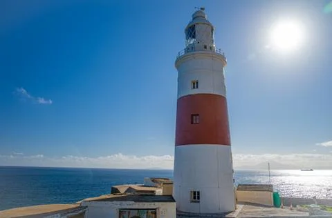 A lighthouse on the coast of the ocean serves to indicate the direction of lost Stock Photos
