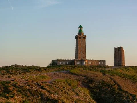 Lighthouse on coastal cliff at sunset Stock Photos