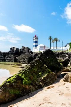 A lighthouse on the edge of some rocks Stock Photos