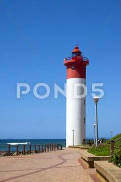 Lighthouse at end of paved walkway at beach Stock Photos