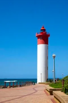 Lighthouse at end of paved walkway at beach Stock Photos