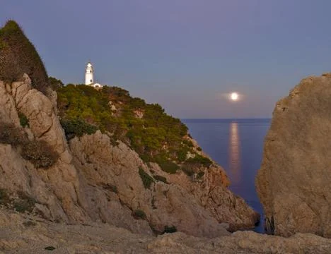 Lighthouse Far de capdepera, dusk, moonbeam on sea,rocks and trees, cala ratj 库存照片