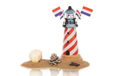 Lighthouse with flags and assorted shells in sand Stock Photos