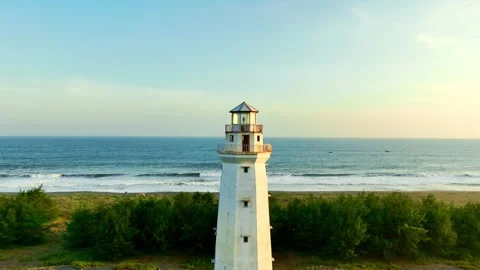 Lighthouse framed by ocean and coastal greenery Stock Footage 335439937