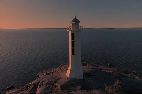 Lighthouse on a granite cliff at sunset Foto stock