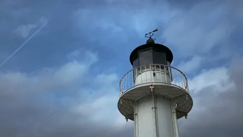 A lighthouse in a harbor with the sky and a flying plane Stock Footage 167590462