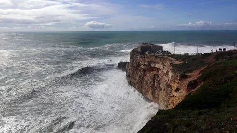 Lighthouse on a high cliff in front of huge ocean waves. Nazare, Portugal Stock Footage
