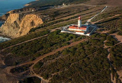 Lighthouse on high cliffs of cape Espichel, Portugal, at sunset Stock Photos