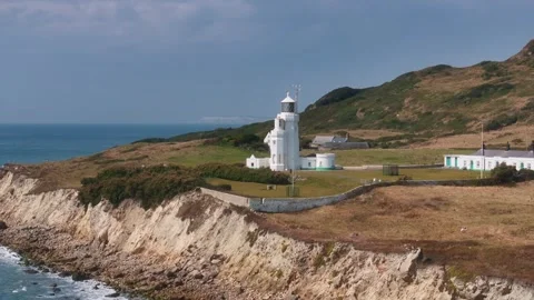 A lighthouse is on a hill overlooking the ocean Stock Footage 297950537