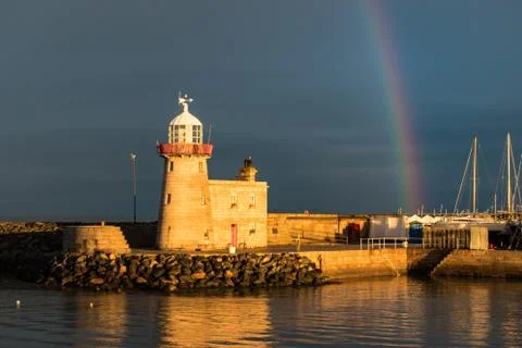 The lighthouse at Howth Harbour in County Dublin in sunlight under a rainbow Foto stock