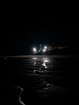 Lighthouse illuminates dark beach Stock Photos