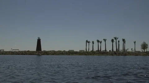 Lighthouse on lakefront pier.  Palm trees in view Stock Footage 52880576
