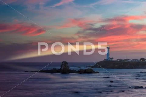 Lighthouse with light beam at sunset Stock Photos