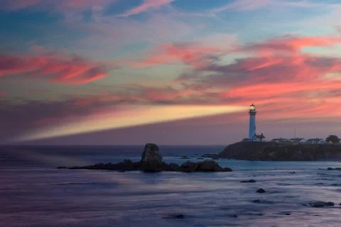 Lighthouse with light beam at sunset Stock Photos