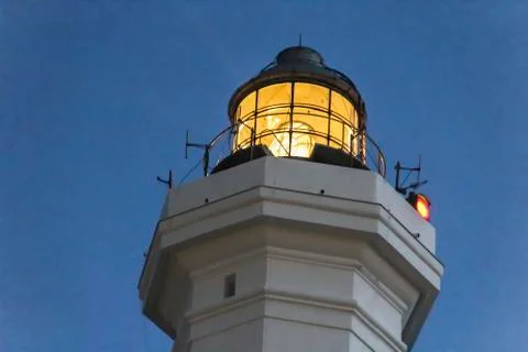 Lighthouse with light beam at sunset Stock Photos