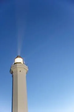 Lighthouse with light beam at sunset Photos
