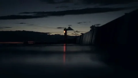 Lighthouse light flashes on the pier reflection in the late evening after sunset Stock-Footage 69205437