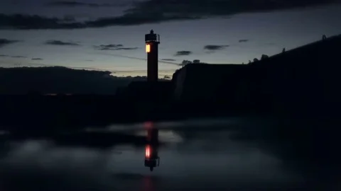 Lighthouse light flashes on the pier reflection in the late evening after sunset Stock Footage 69205459