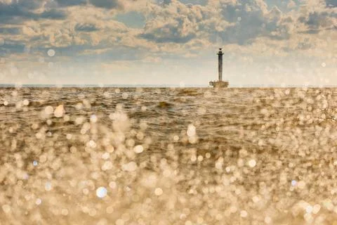 Lighthouse of marine navigation through splashing water at sunset, sailing boat Stock-Fotos