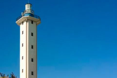Lighthouse at noon on a clear day on empty blue sky background. Wallpaper on  Stock Photos