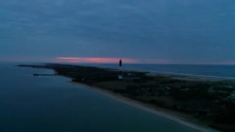 Lighthouse on the ocean beach casting beam of light moments before a Sunrise. Stock Footage 323782957