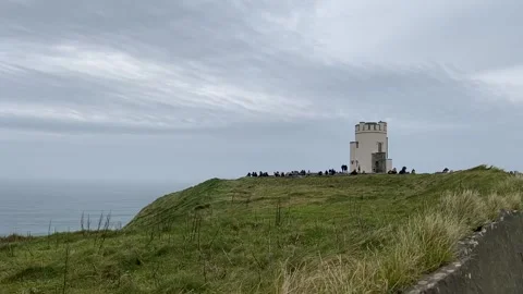 Lighthouse at the other end of the Cliffs of Moher Stock Footage 130361627