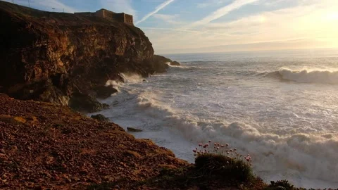 Lighthouse over the Atlantic Ocean at sunset in the town of Nazare in Portugal Stock Footage 220203339