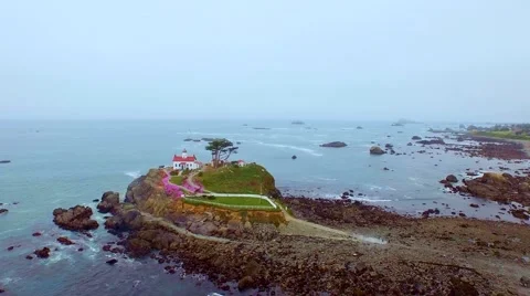 A lighthouse in the Pacific northwest surrounded by blooming pink flowers Stock Footage 52138226