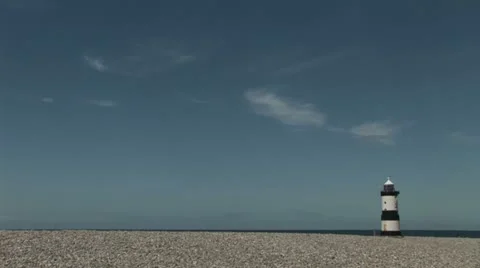 Lighthouse with pebbles on a beach in foreground Stock Footage