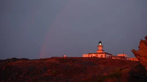 Lighthouse with rainbow at sunrise while raining on the sunset Stock Footage 297792425