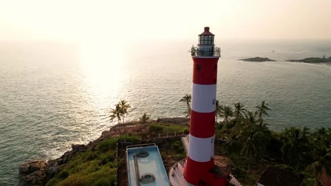Lighthouse with red and white stripes at sunset, aerial view. Kovalam Beach Stock Footage 282298724