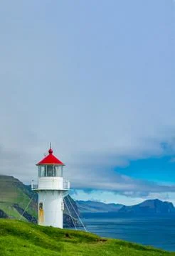Lighthouse with red cap under the cloudy sky Stock Photos