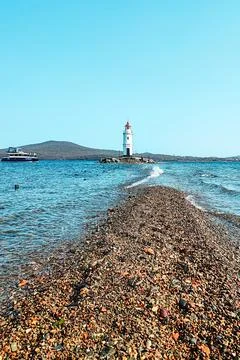 Lighthouse with a red rocky path at the end surrounded by the sea next to a.. Stock Photos