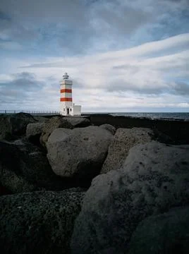 Lighthouse with red stripes wide angle over the black rocks Stock Photos