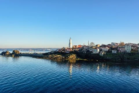 Lighthouse reflection on sea under clear blue skies Stock Photos