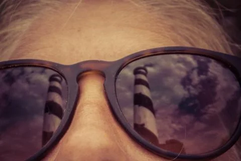 Lighthouse reflection in sunglasses weared by young beautiful blonde woman. V Foto stock